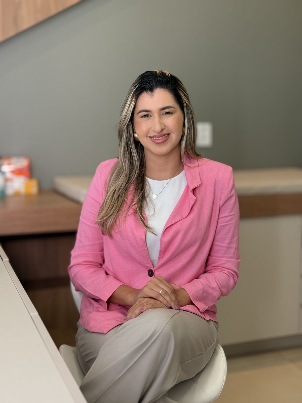 Chirley Reis sentada no consultório, sorrindo